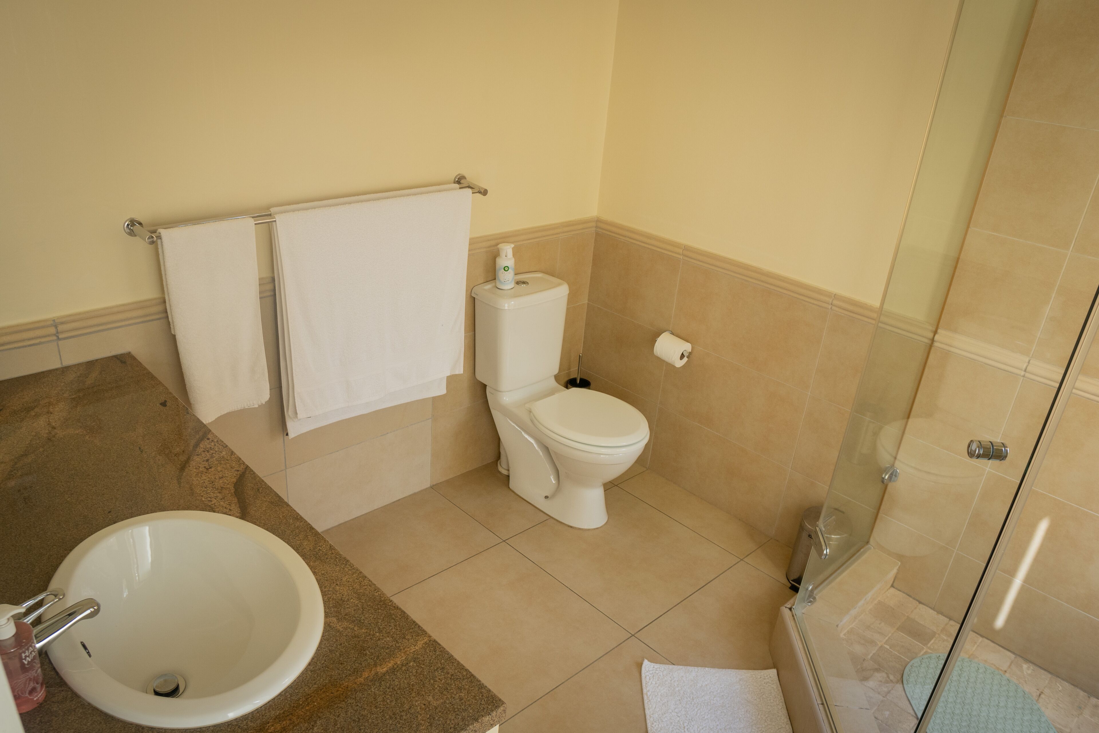 Ein Badezimmer mit Waschbecken, Toilette und Duschkabine aus Glas.