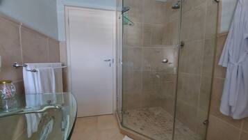 Un baño con cabina de ducha de vidrio, lavamanos de vidrio y una puerta blanca.