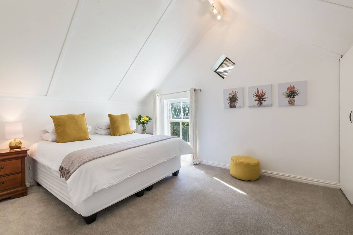 A bedroom with a bed, a nightstand, a window, and a door.