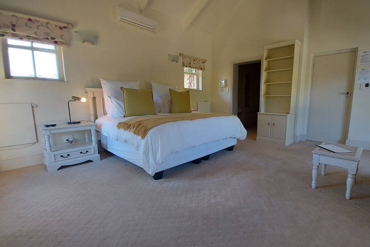 A bedroom with a bed, bedside tables, a chair, a wardrobe, and a window.