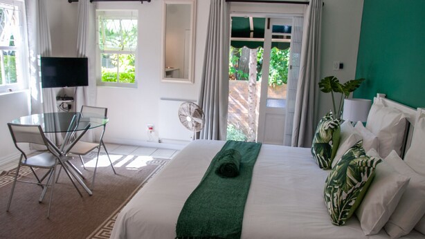 Een hotelkamer met een bed, een bureau met stoel, een televisie en uitzicht op groen.