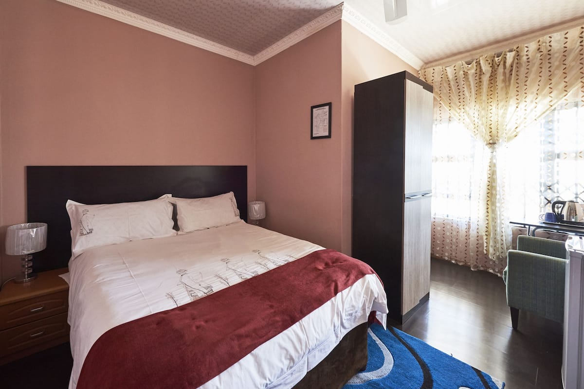 A hotel room with a bed, a nightstand, a desk, and a chair.