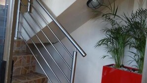 A staircase with a metal railing leading to a reception area marked by a sign. - Flossie’s Bed and Breakfast (Soweto)