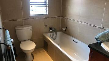 A bathroom with a toilet, bathtub, and sink.
