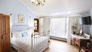 Une chambre à coucher avec un lit, une armoire en bois, un bureau avec un miroir et un téléviseur.