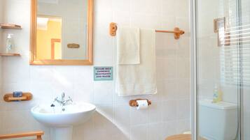 A bathroom with a sink, mirror, towel rack, and a sign encouraging to conserve electricity and water.
