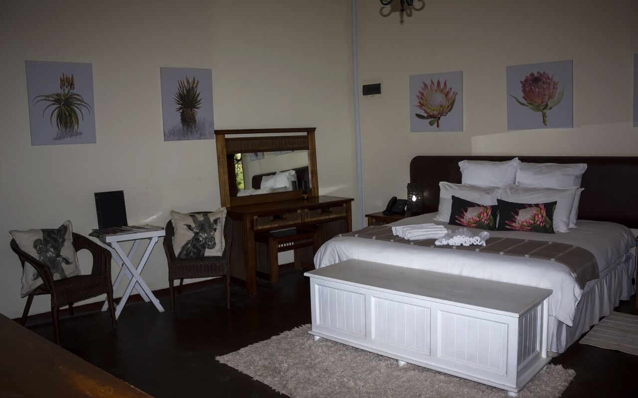 Quarto com cama, mesa de cabeceira, cadeira, escrivaninha e espelho.