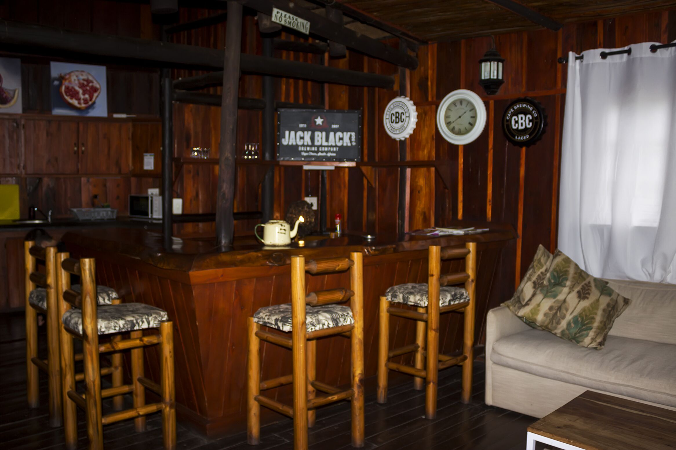 Zona de bar con mobiliario de madera, un letrero que dice "Jack Black" y un reloj en la pared.