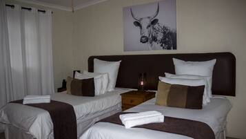 A hotel room with two beds, a headboard, a nightstand, and a wall-mounted artwork of a bull.