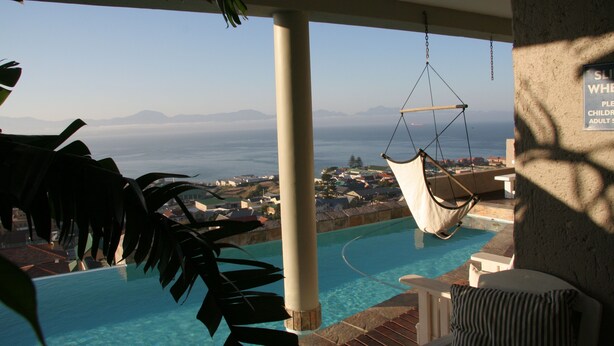 A pool area with a hanging chair and a view of the sea. - 3 Colours Blue (Mossel Bay)