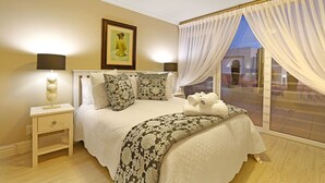 Un dormitorio con cama, mesita de noche y vista a un patio.