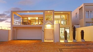 Una casa moderna de dos pisos con garaje, ventanas amplias y una entrada bien iluminada.