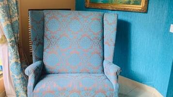 Una habitación con un sillón estampado, una mesa de centro de mármol y un cuadro enmarcado en la pared.