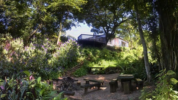 Un giardino con un pontile in legno, tavoli da picnic e un vialetto in pietra.