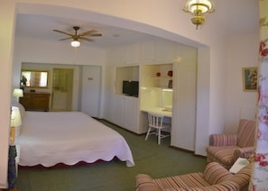 Un dormitorio con cama, escritorio, silla y televisor.
