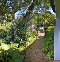 Un sendero de ladrillo que conduce a un espacio cubierto, con un edificio blanco al fondo.