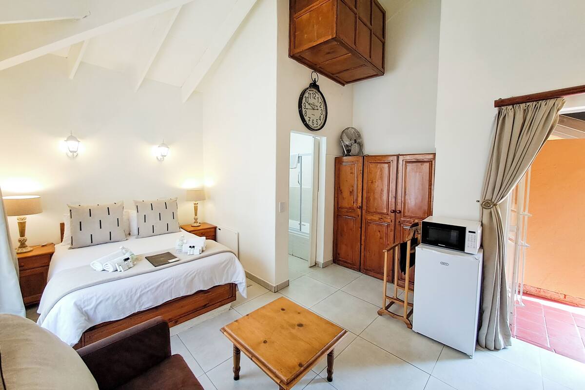 A bedroom with a bed, bedside tables, a wooden cabinet, a microwave, and a small table.