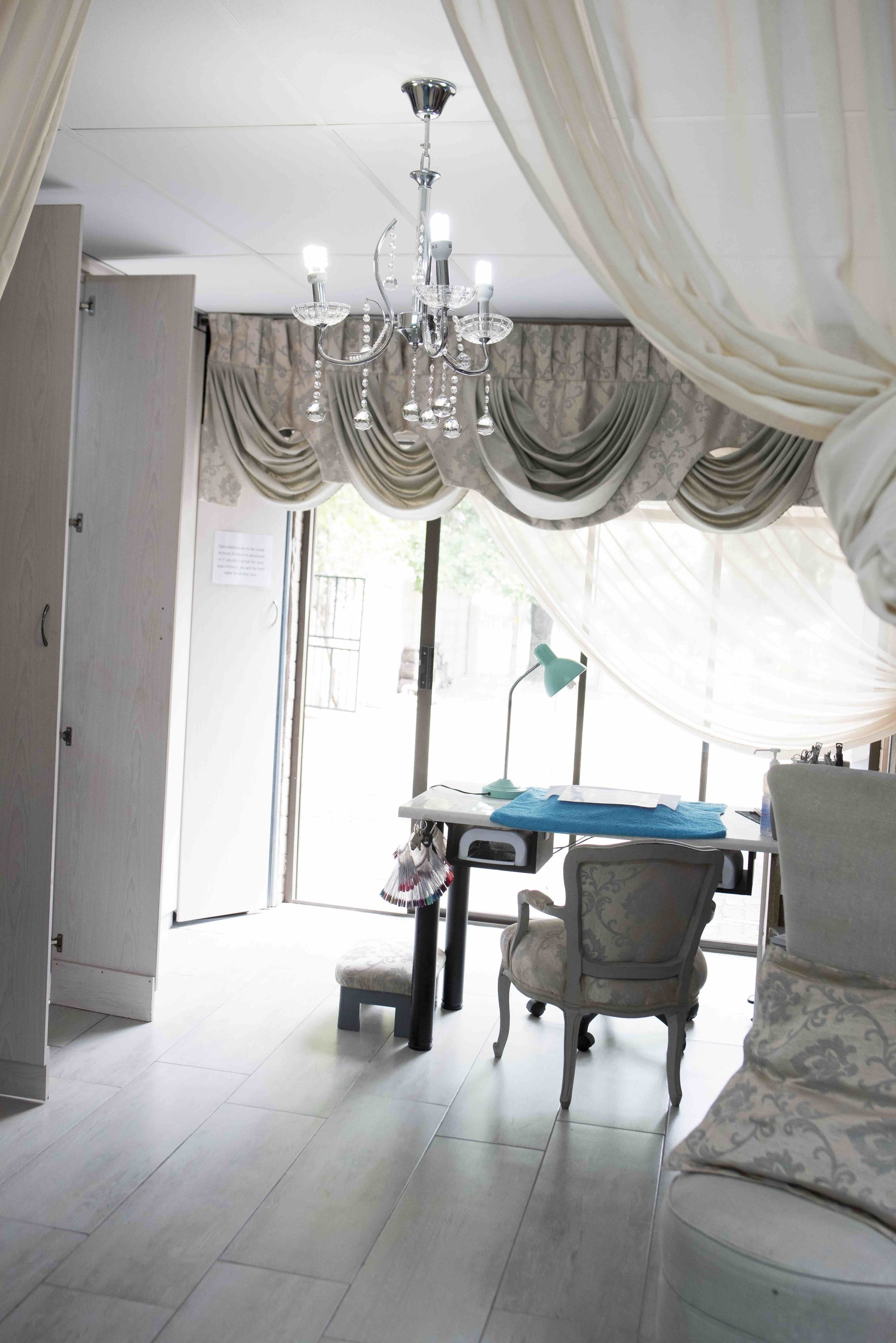 A room with a chandelier, a table with a blue tablecloth, a patterned armchair, and a sofa.