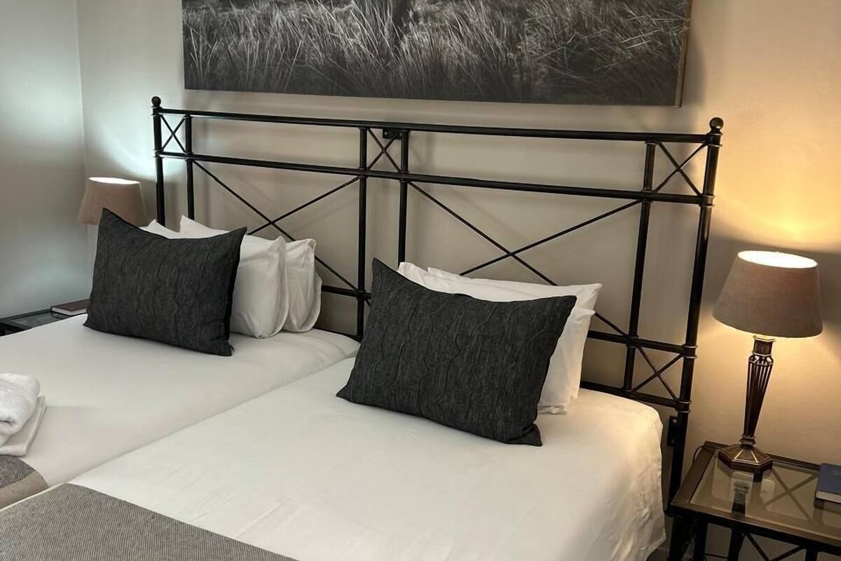 A double bed with a metal headboard, two bedside tables with lamps, and a large wall-mounted picture of a bull.