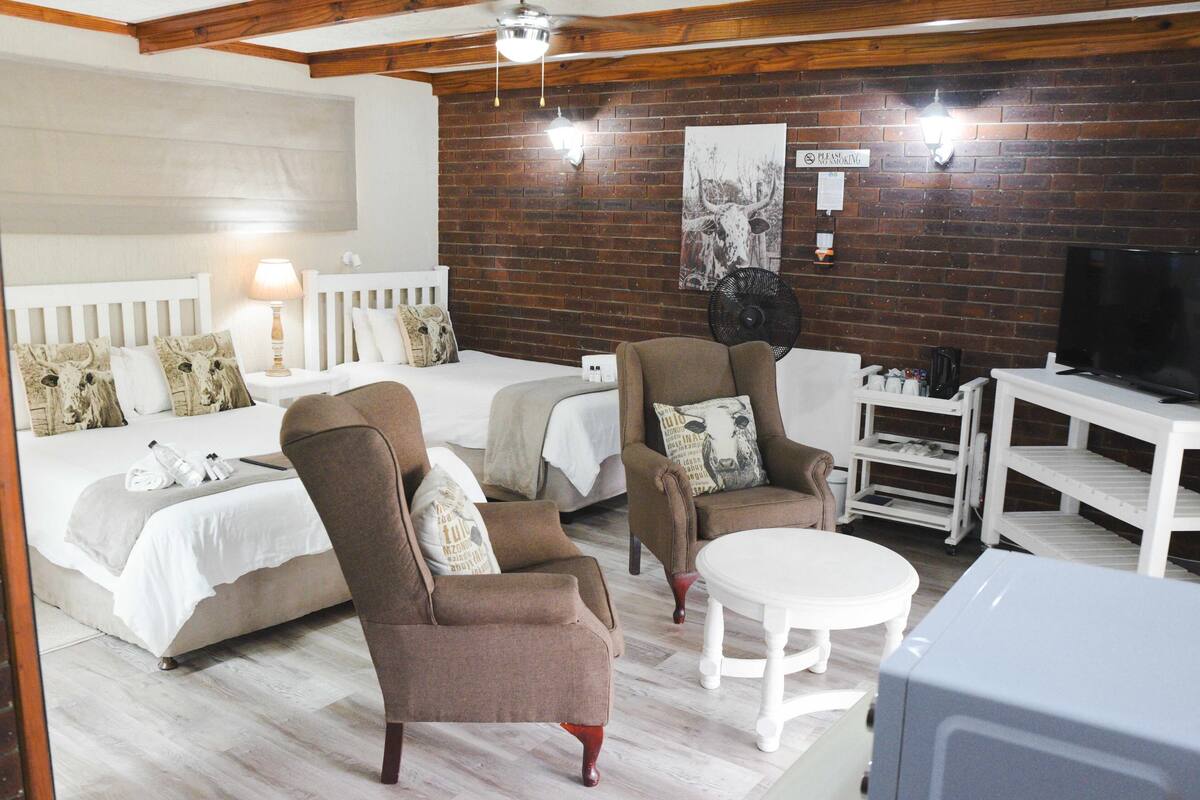 A room with two beds, a sofa, a table, and a TV.