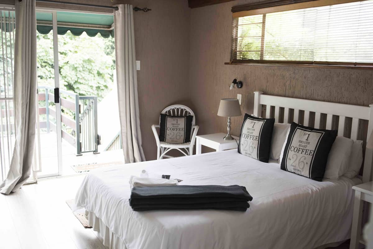A hotel room with a bed, a chair, a table, and a window.