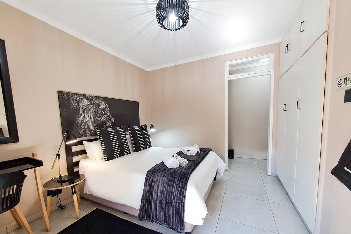 A modern bedroom with a bed, bedside table, lamp, and a wardrobe.