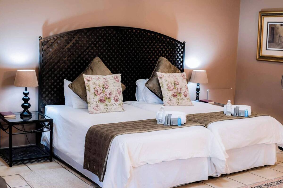 A double bed with a dark headboard, two bedside tables with lamps, and floral-patterned pillows.