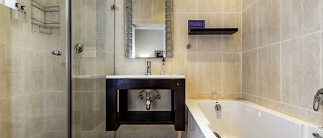 A modern bathroom with a glass-enclosed shower, a large mirror, a white bathtub, and a dark wooden vanity.