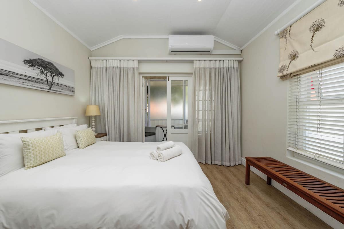Habitación de hotel con una cama grande, un banco, un escritorio y una ventana con cortinas.