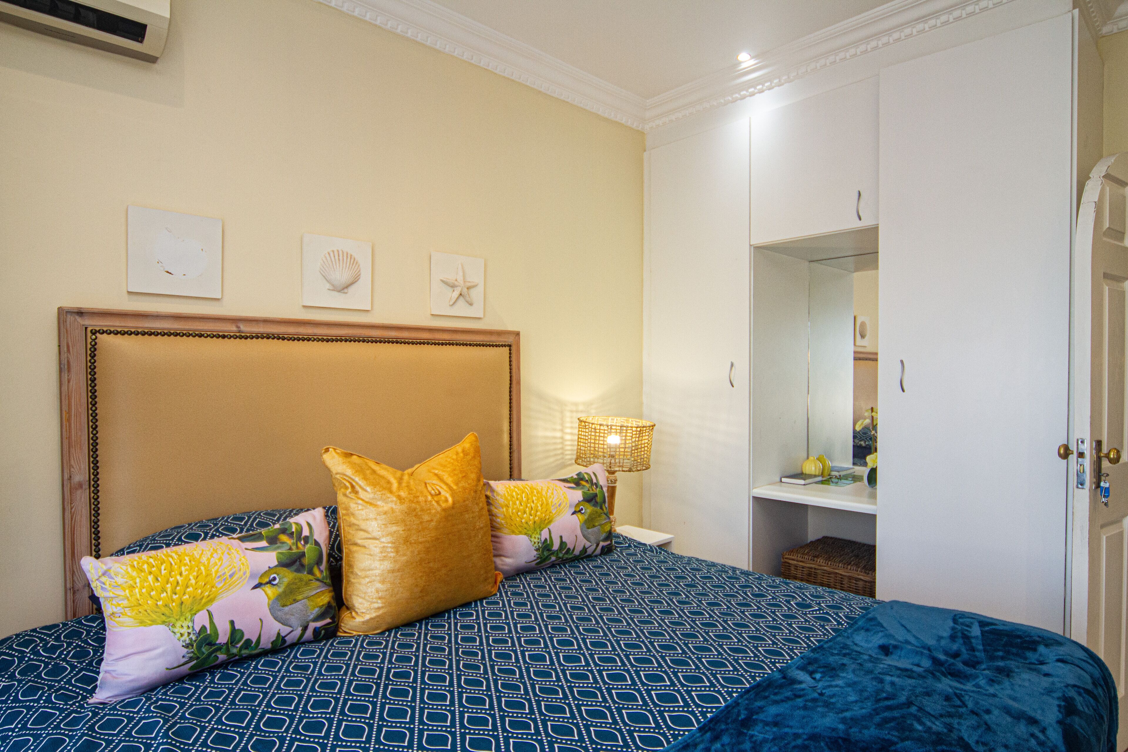 Une chambre à coucher comprenant un lit, des oreillers, une table de chevet, une lampe, une armoire et des éléments de décoration murale.