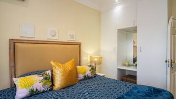 Une chambre à coucher comprenant un lit, des oreillers, une table de chevet, une lampe, une armoire et des éléments de décoration murale.