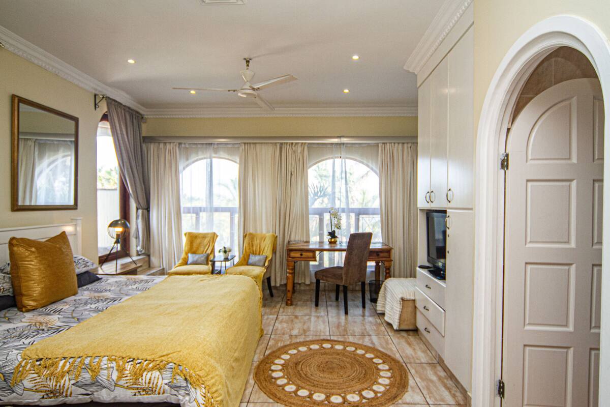 A bedroom with a bed, a desk, a chair, and a television.