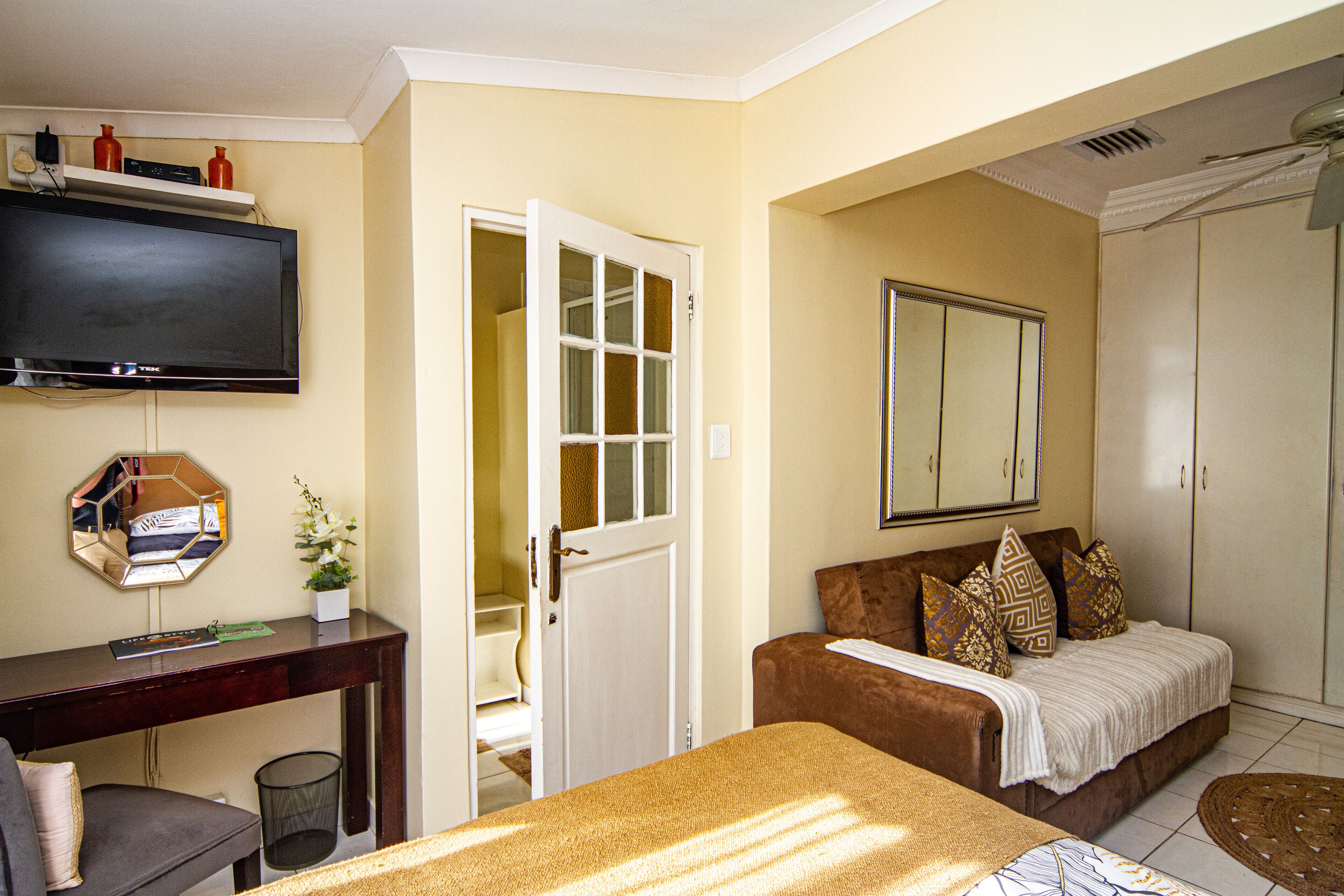 A hotel room with a bed, a sofa, a TV, a desk, and a wardrobe.