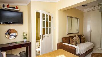 A hotel room with a bed, a sofa, a TV, a desk, and a wardrobe.