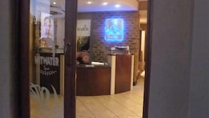 Un espace d'accueil avec un mur en pierre et un panneau lumineux au néon.