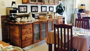 A kitchen with wooden cabinets, a coffee machine, and a dining area with a table and chairs.