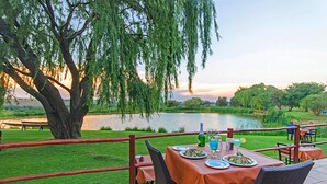 Une table à manger installée à l  ’extérieur, avec vue sur un lac et des arbres.