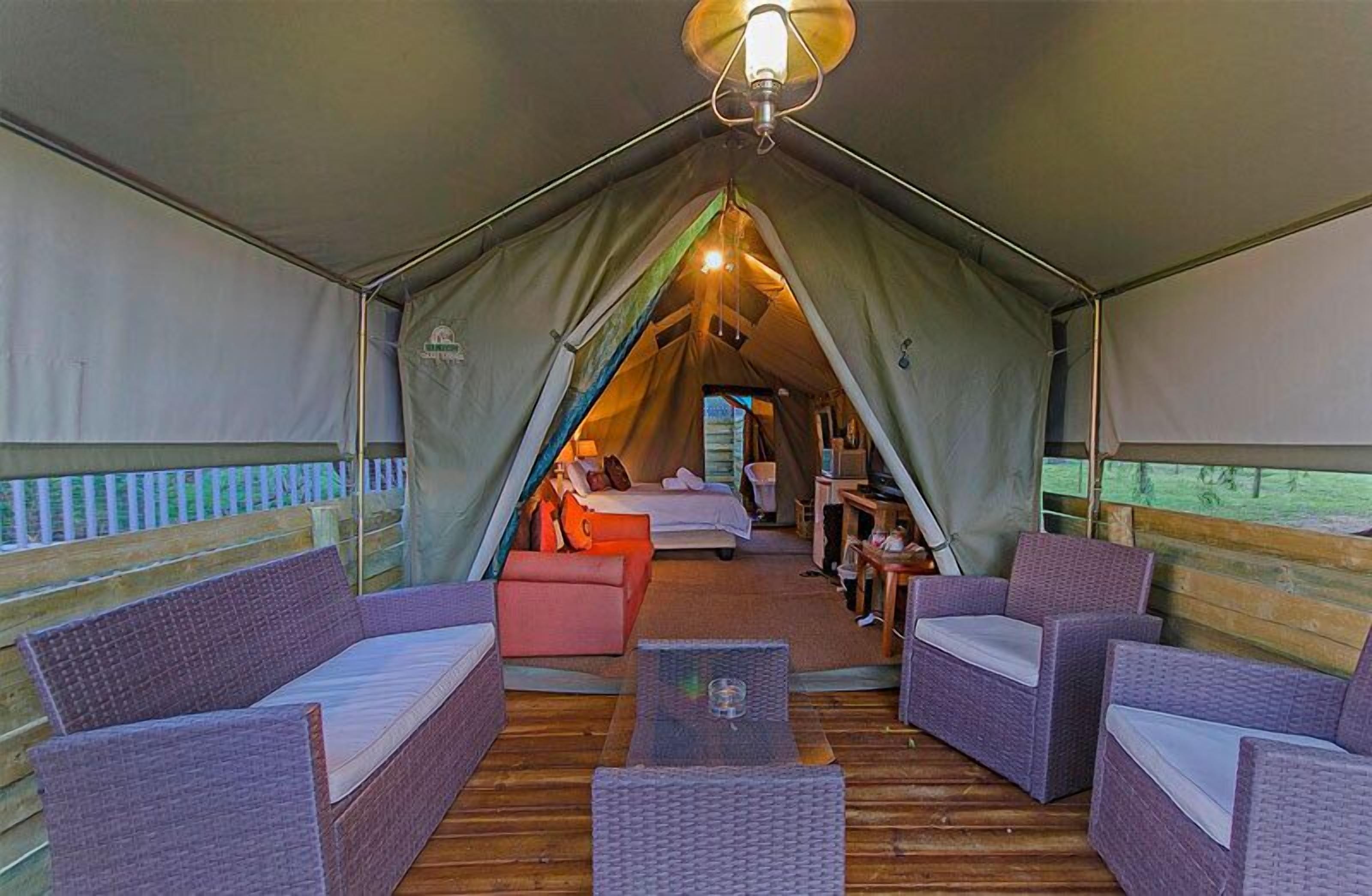 A cozy tented accommodation with a bed, seating area, and a small table.