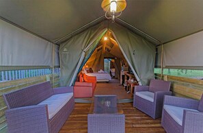 A cozy tented accommodation with a bed, seating area, and a small table.