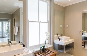 A modern bathroom with two sinks, a large window, and a mirror.