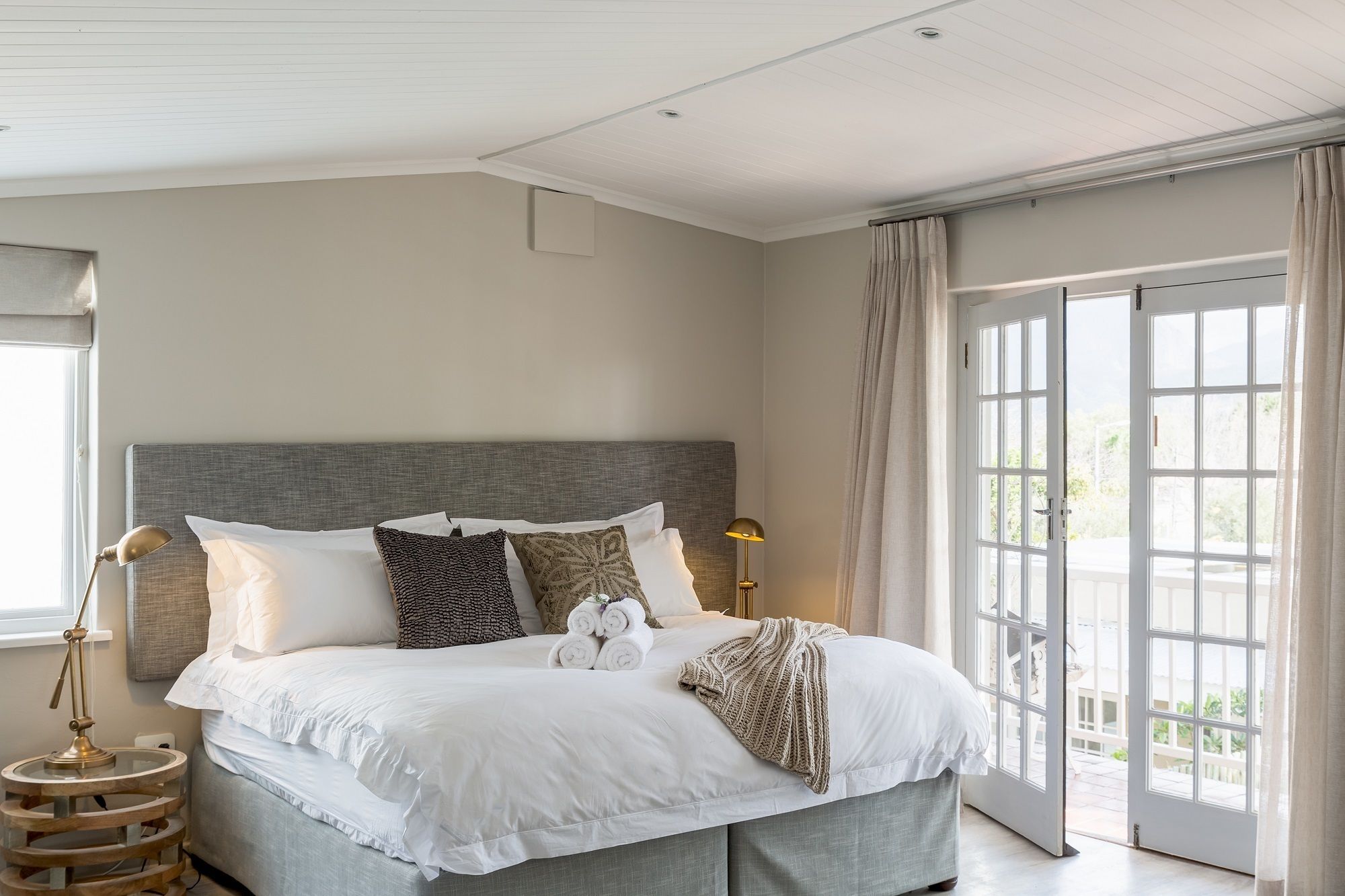Een slaapkamer met een groot bed, een bedlampje en uitzicht op de omgeving door een schuifdeur.