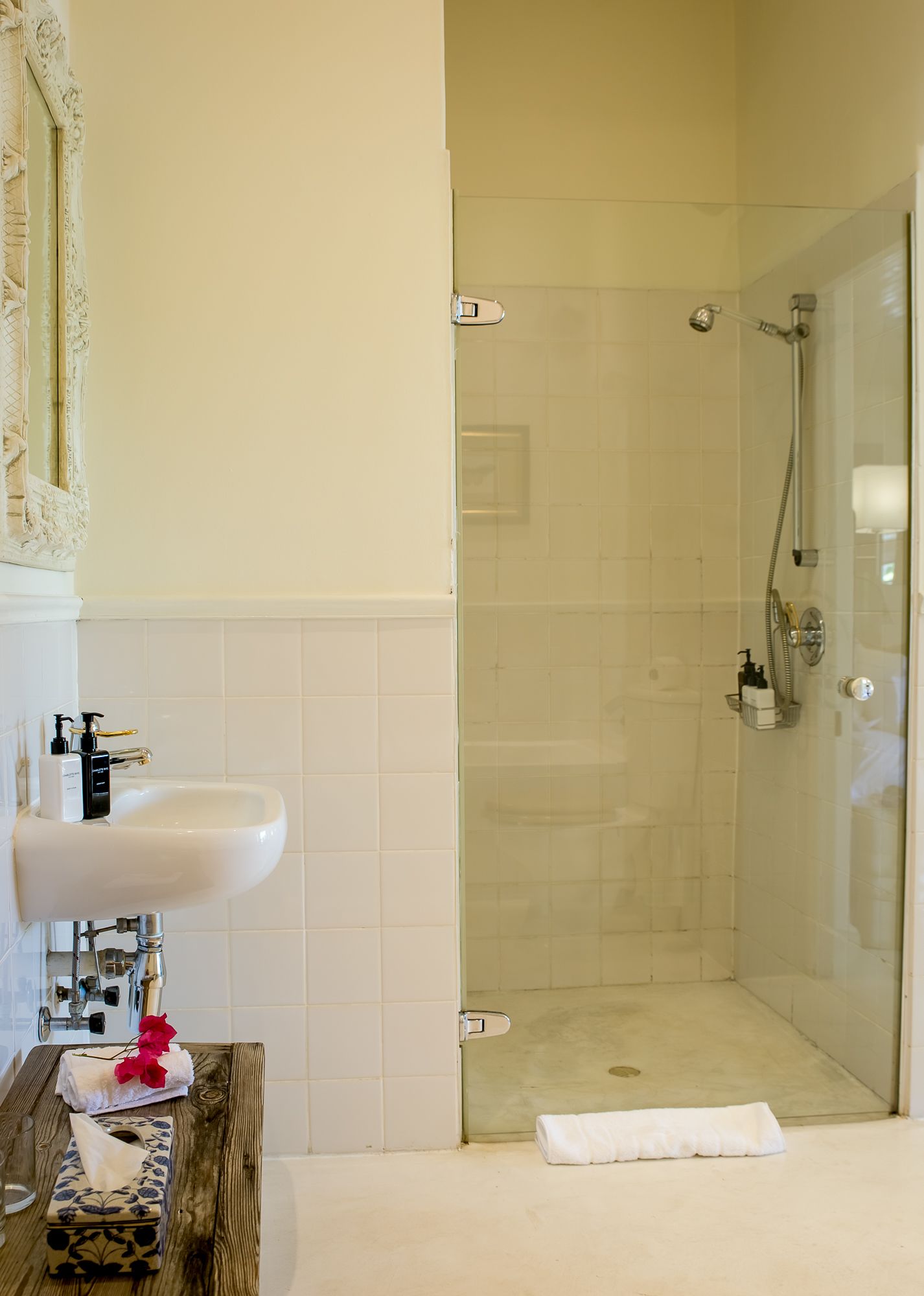 A bathroom with a white sink, a glass shower enclosure, and a wooden vanity.