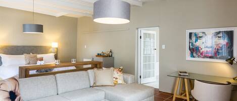 Un soggiorno moderno con un divano grigio, un tavolino in legno, una lampada a sospensione e un quadro appeso al muro.