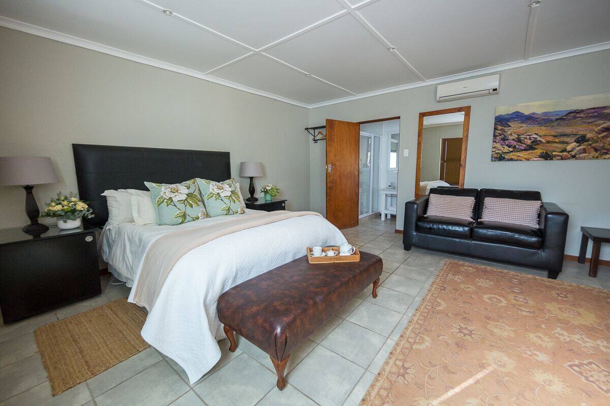 A bedroom with a bed, bedside tables, a bench, a sofa, and a rug.