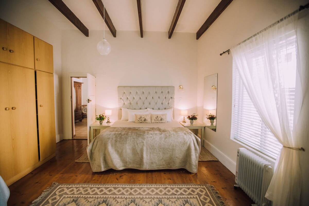 A bedroom with a large bed, wooden wardrobe, and a radiator.