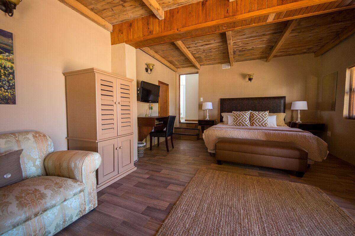 A bedroom with a bed, a sofa, a desk, and a wardrobe.