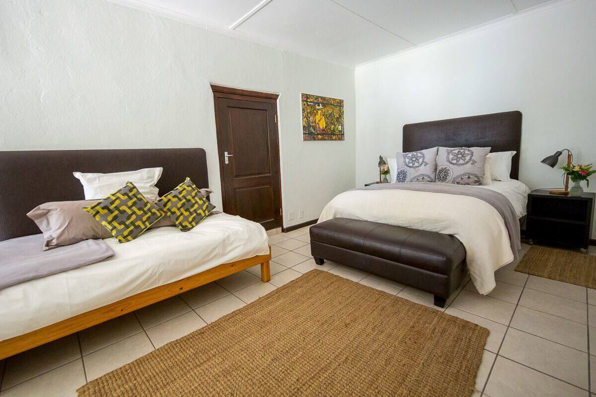 A bedroom with two beds, a brown door, and a wall-mounted artwork.