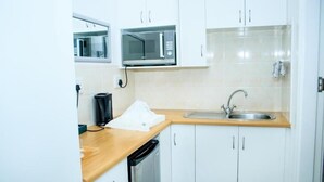 A compact kitchen with white cabinets, a microwave, a sink, and a dishwasher. - Anchorage Guest House (Gqeberha (Port Elizabeth))