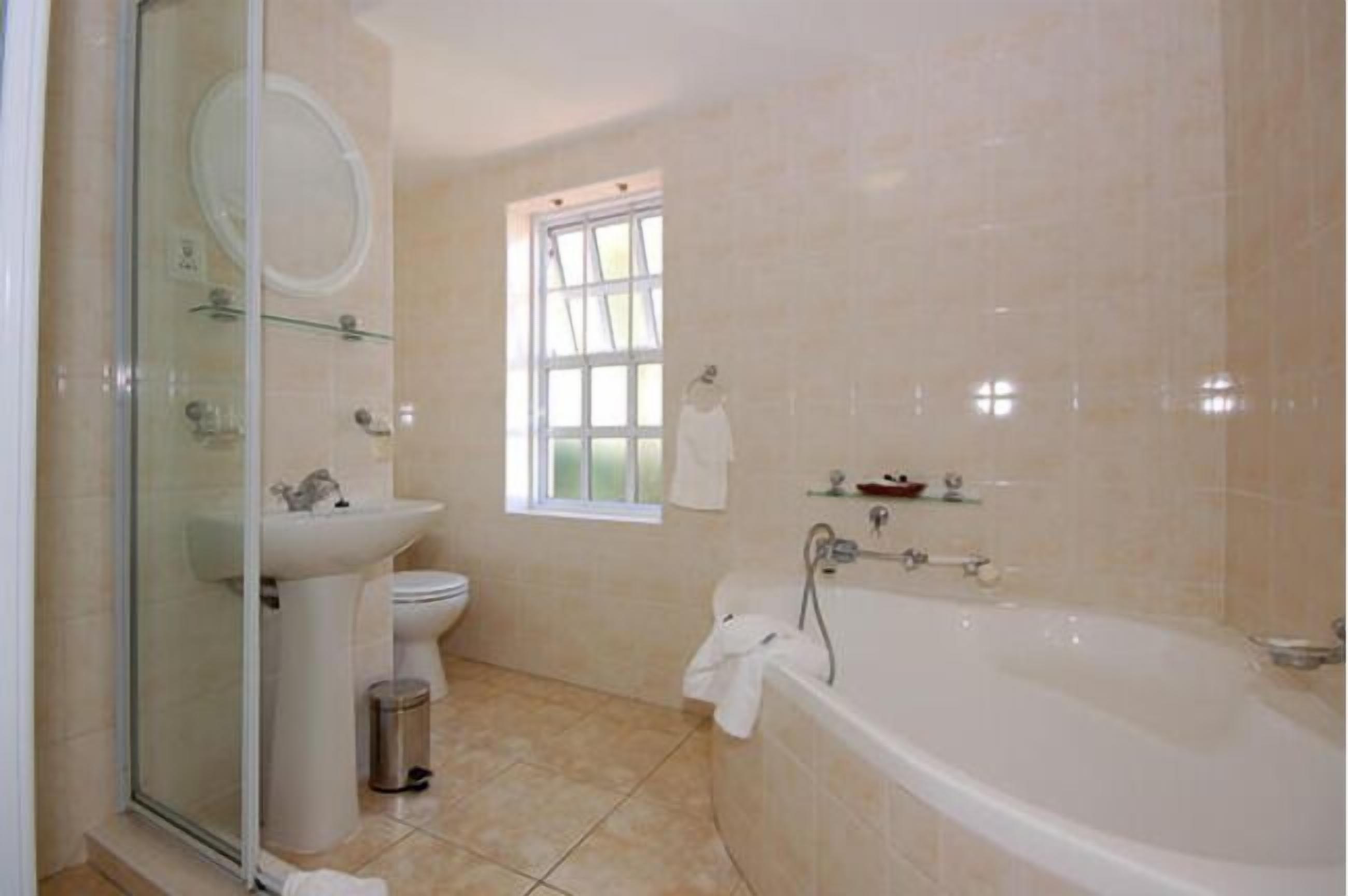 Un baño con cabina de ducha de vidrio, lavamanos, inodoro, bañera y ventana.