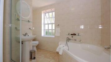 Un baño con cabina de ducha de vidrio, lavamanos, inodoro, bañera y ventana.